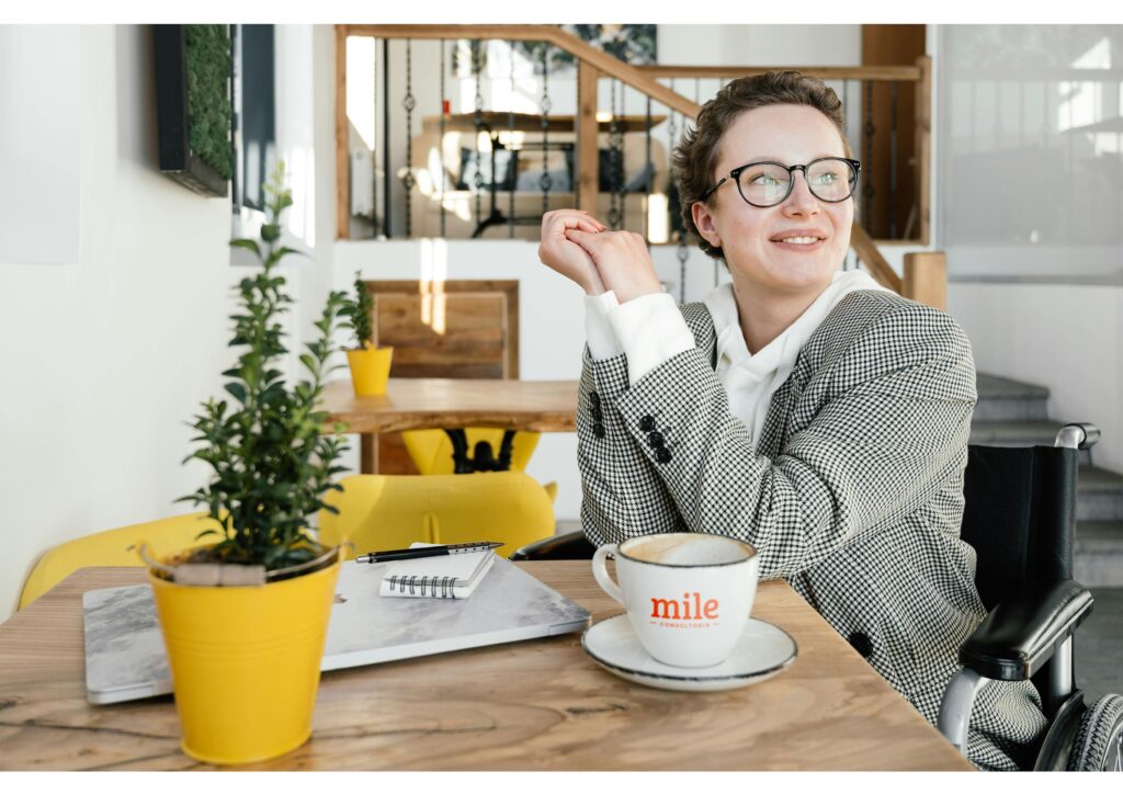Mulher pensando em carreira sentada diante de uma mesa com café