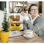 Mulher pensando em carreira sentada diante de uma mesa com café